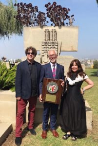 The AVA team standing outside the Hollyhock House in front of a tan-colored statue with Hollyhock House Curator Jeffrey Herr